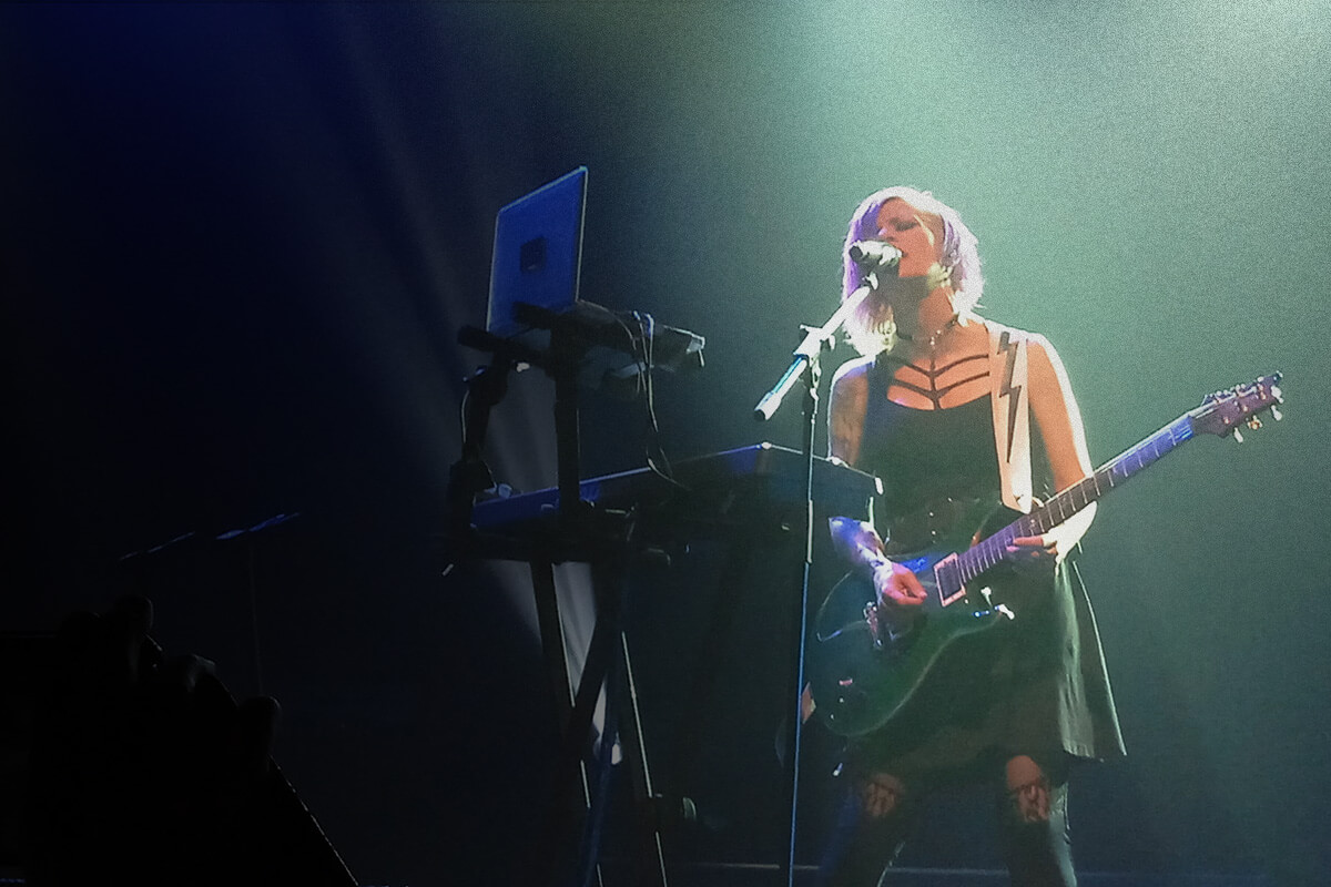 Woman performing with a guitar on stage