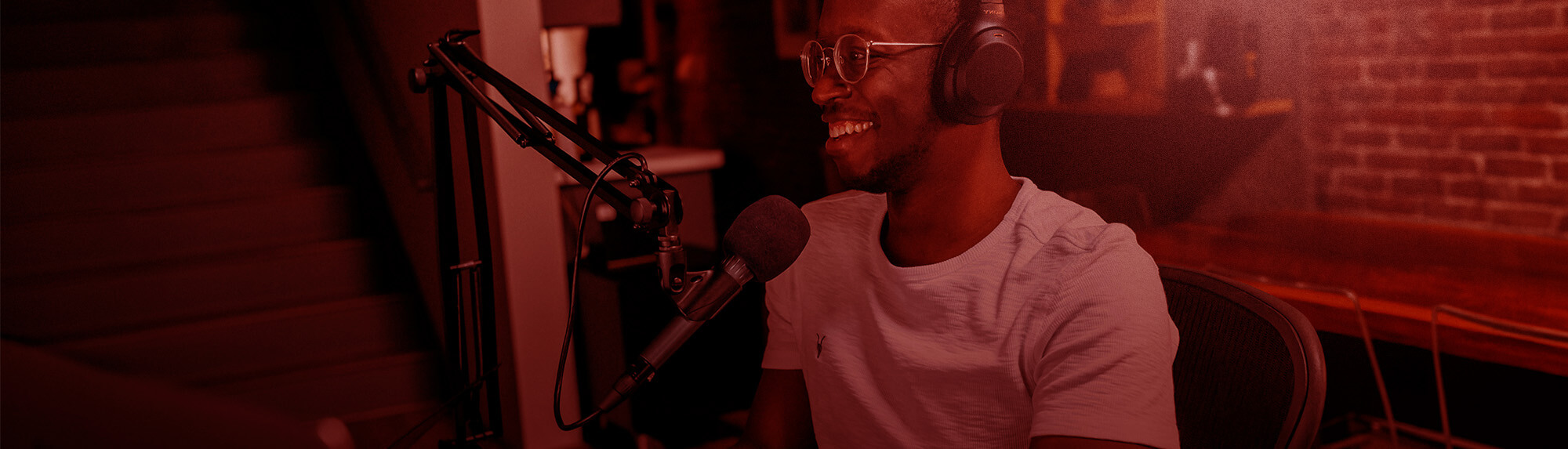 Man smiling and recording talking into a microphone