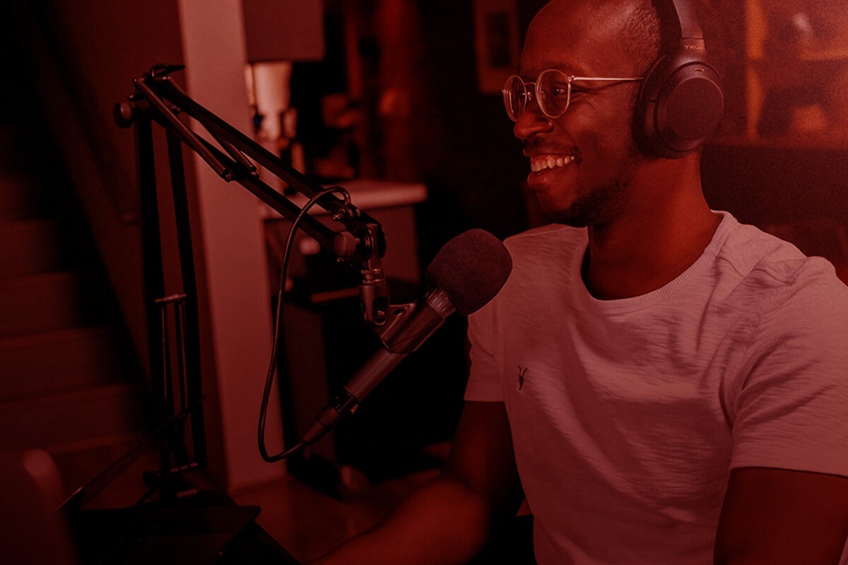 Man smiling and recording talking into a microphone