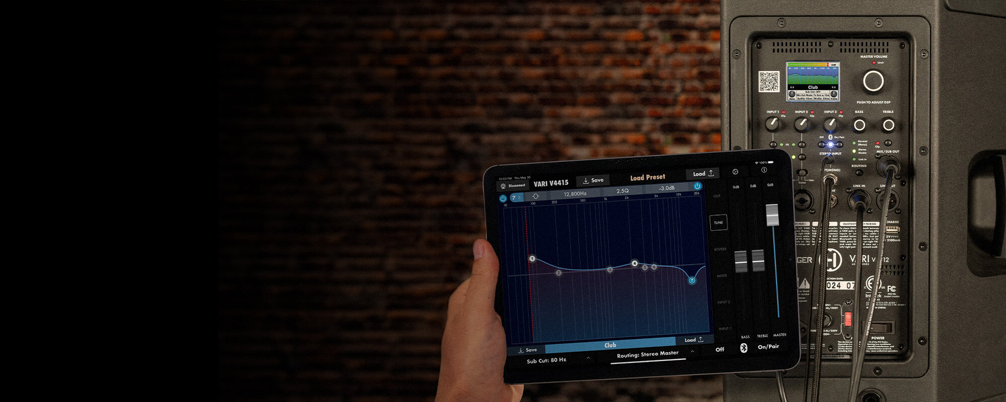 A hand holding an ipad with the Vari App up to the back of a V4400 speaker