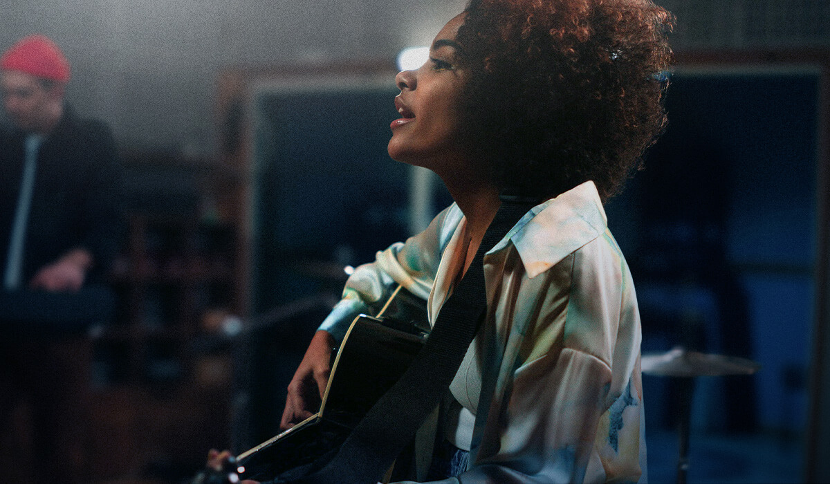 A woman recording singing and playing guitar