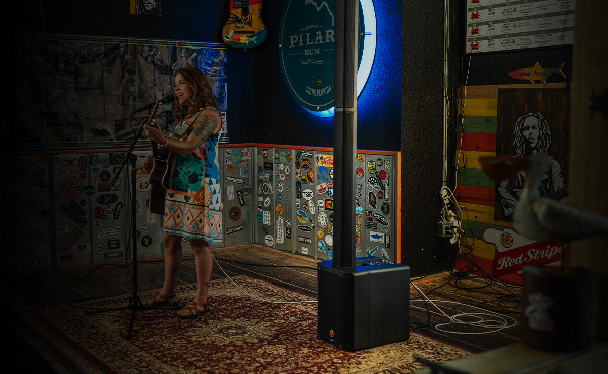 Woman playing guitar and using a Harbinger Portable Line Array MLS1000