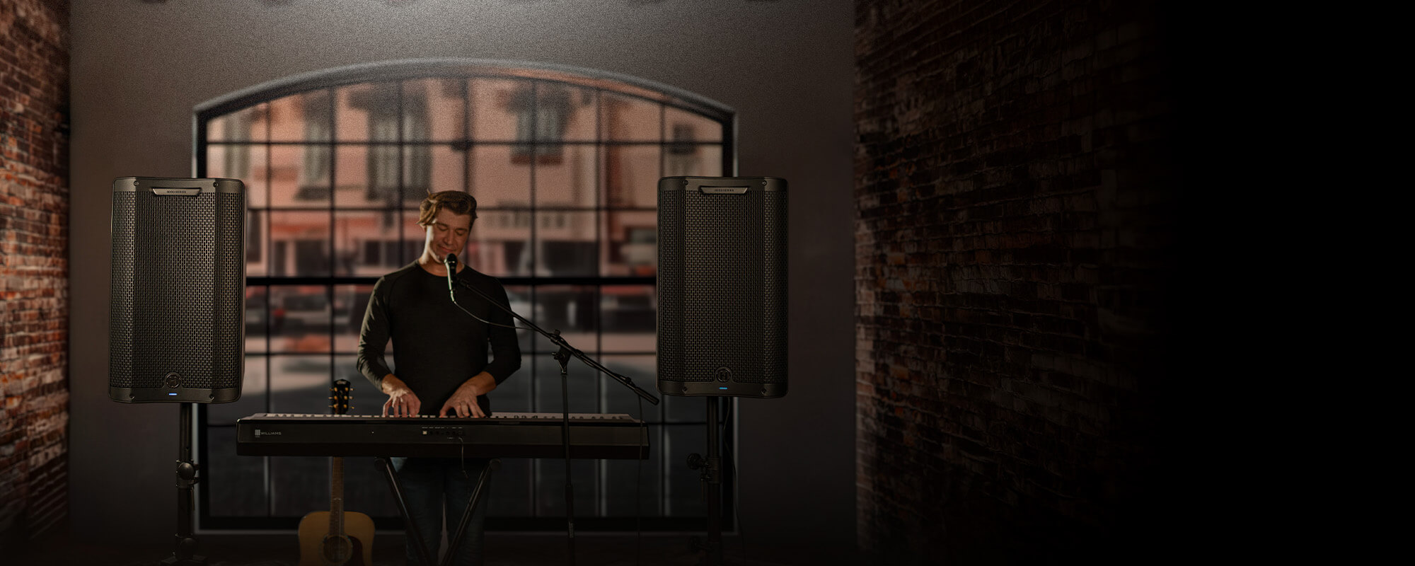 Man playing piano in front of a window using two Harbinger Vari Series 4400 speakers