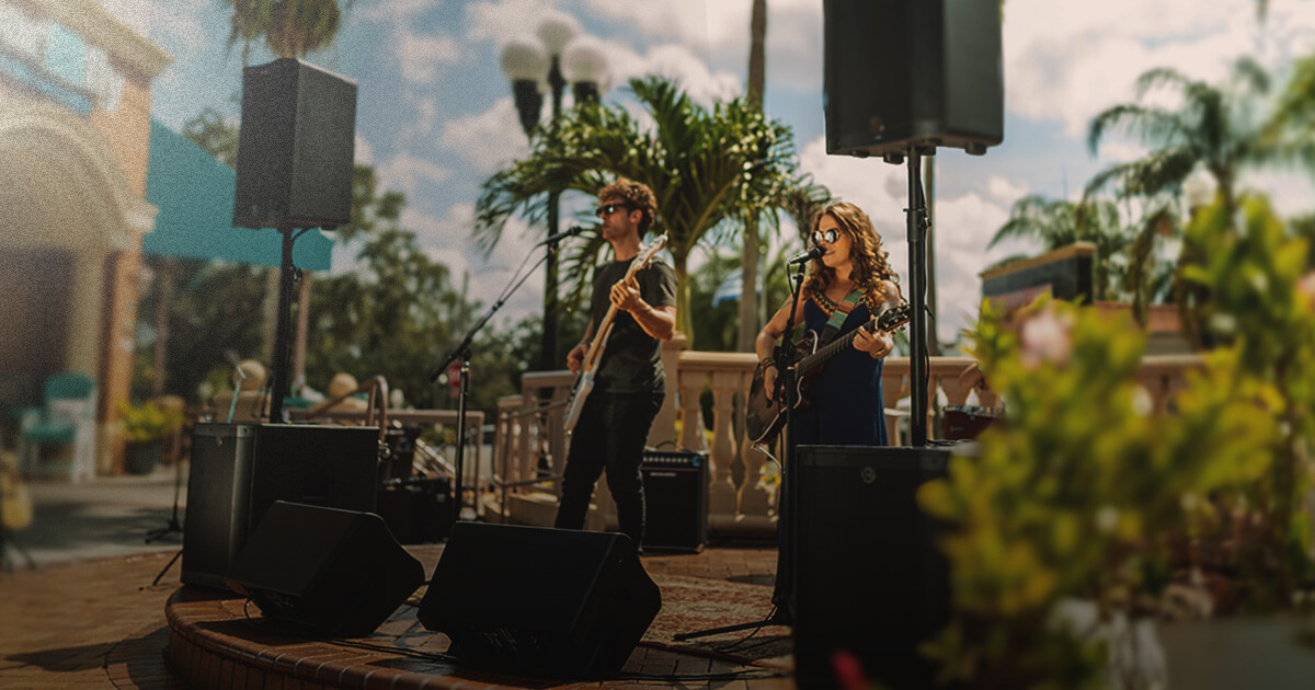 Harbinger Vari Speakers and Subs set up on outdoor stage with a live band